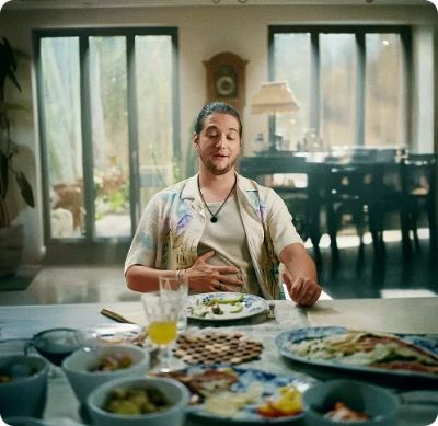 Homem sentado em uma mesa, visivelmente satisfeito, com uma mão sobre o estômago.